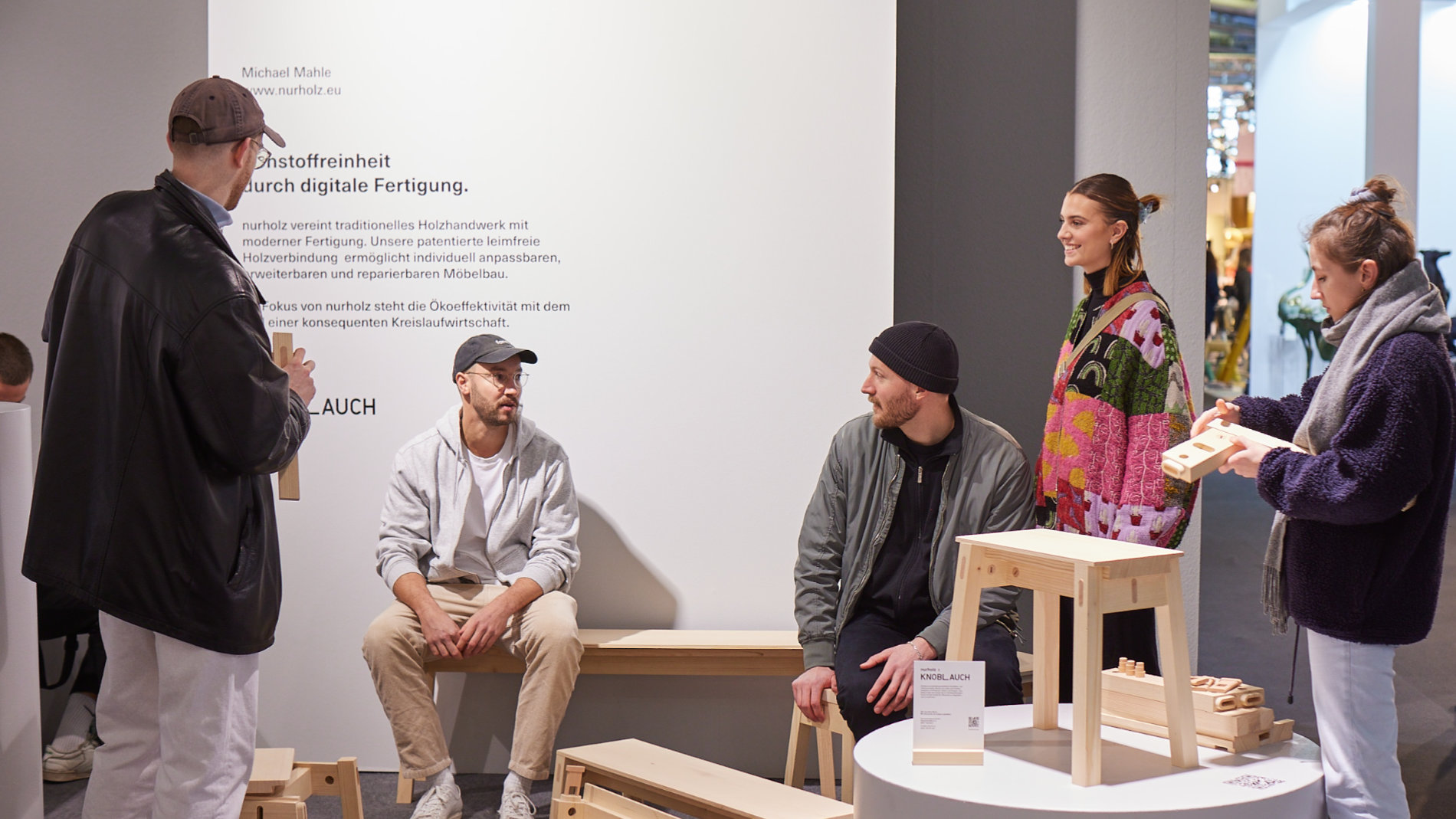 Junge Leute an einem Stand mit Holzmöbel bei Talents auf der Ambiente