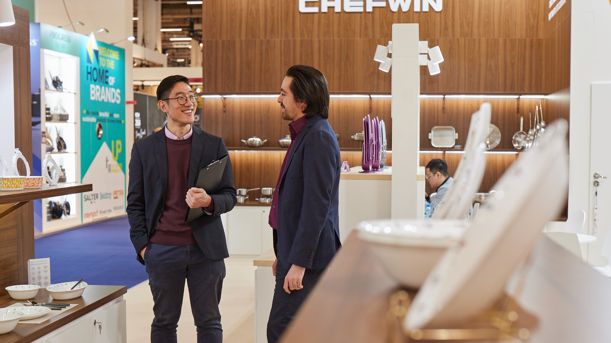 2 men in conversation at a stand with tableware at Ambiente